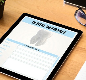 Dental insurance form on tablet next to office supplies