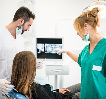 Dentist team member and patient looking at dental x-rays