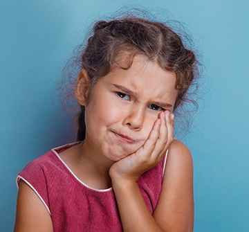 Little girl holding cheek