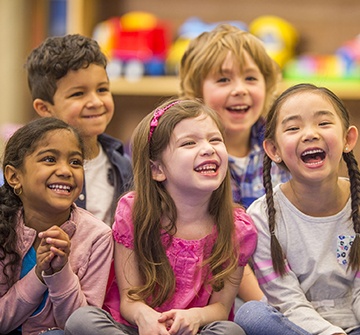 Five kids laughing in a classroom