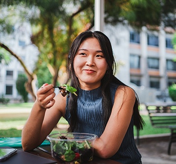 Teen smiling while eating salad outside