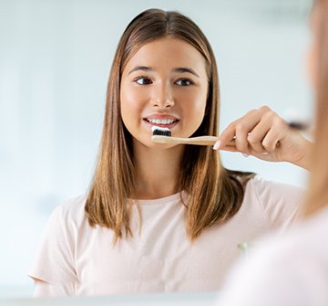Teen girl smiling while brushing her teeth