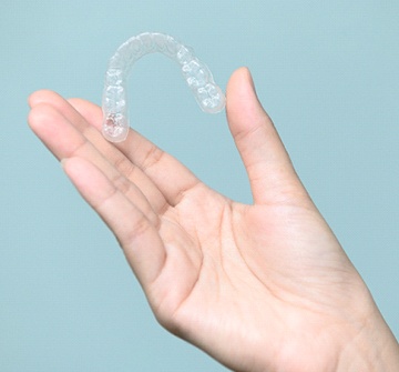 A person holding an Invisalign aligner
