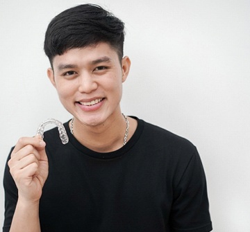 A young male holding an Invisalign aligner