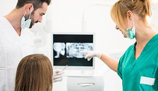 Dentist assistant and patient looking at x-rays