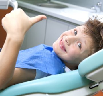 Little boy in dental chair giving thumbs up