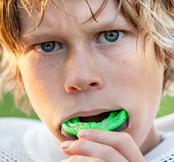 Teen boy placing green mouthguard