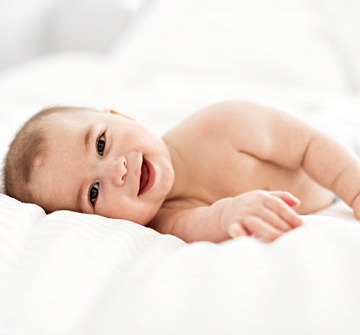 Smiling baby lying on a bed