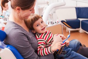 mother holding child in dentist chair