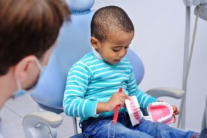 dentist showing child how to brush teeth