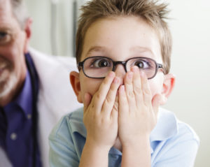 Young boy covers his mouth in surprise hearing about cavities