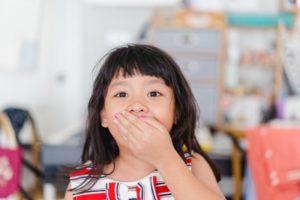 Young girl covers her mouth while visiting her Fitchburg children's dentist