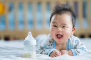 Baby with bottle and healthy smile thanks to Fitchburg pediatric dentist