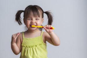 Girl brushing her teeth with fluoride for kids