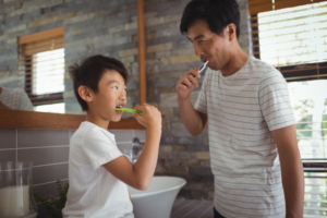 a child and his parent brushing their teeth